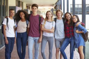 Teenage classmates standing in high school hallway